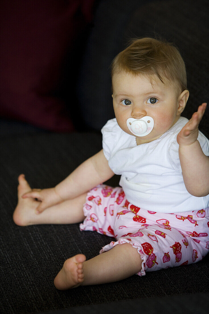 Baby (8 Monate) mit einem Schnuller blickt in die Kamera, Wien, Österreich