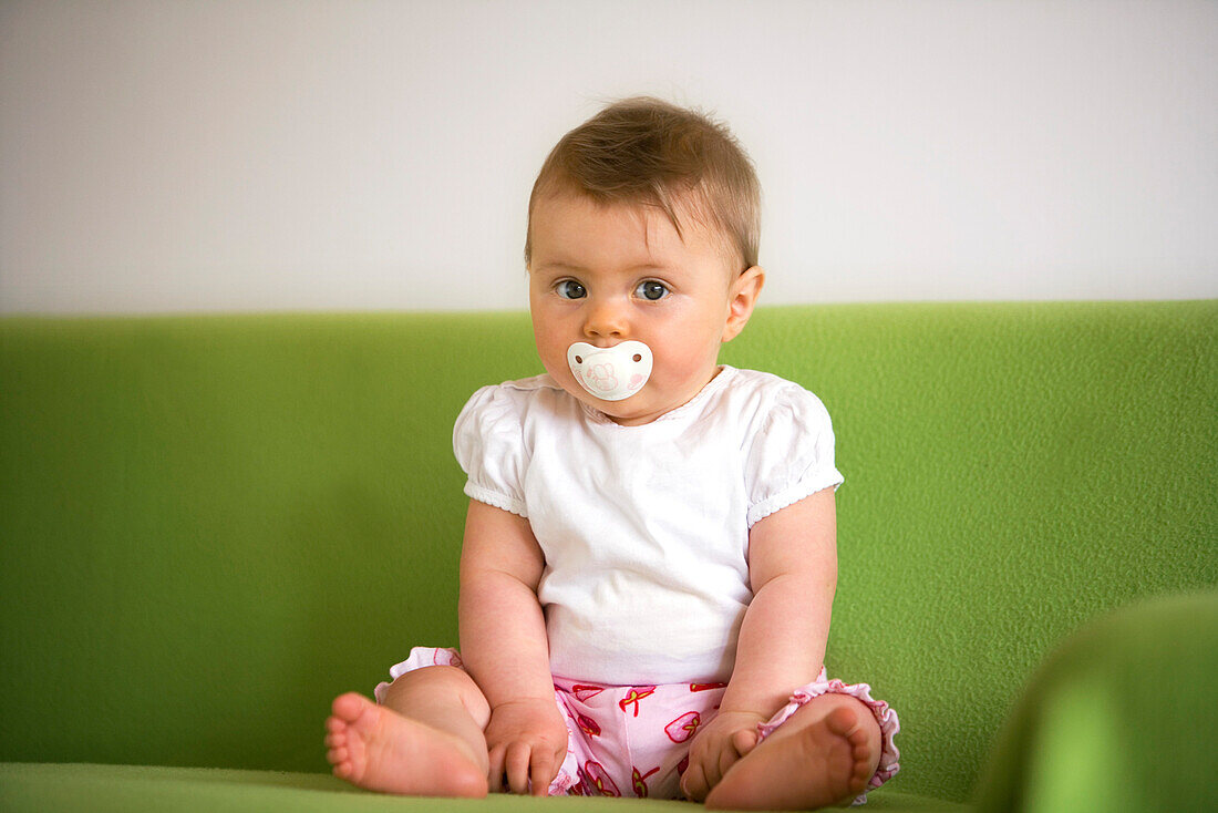 Baby girl (8 Month) useing pacifier looking at camera, Vienna, Austria