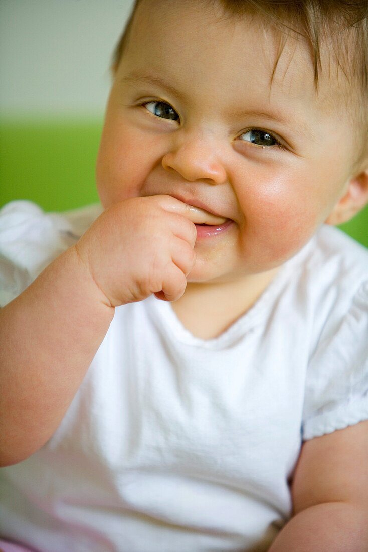 Baby (8 Monate) mit Finger im Mund lacht, Wien, Österreich