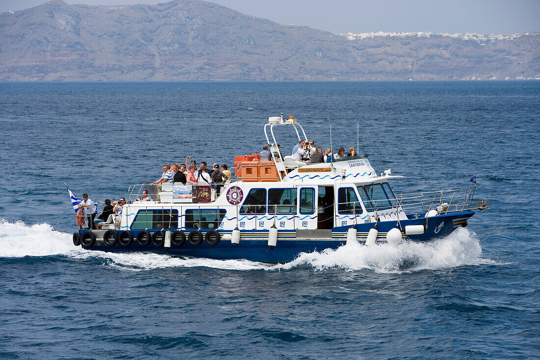 People on a ferry in front of Santorini island, Greece, Europe