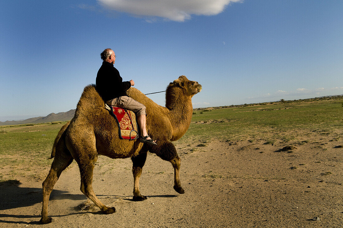 A Foreigner traveler enjoys a ride on a Bactrian camel