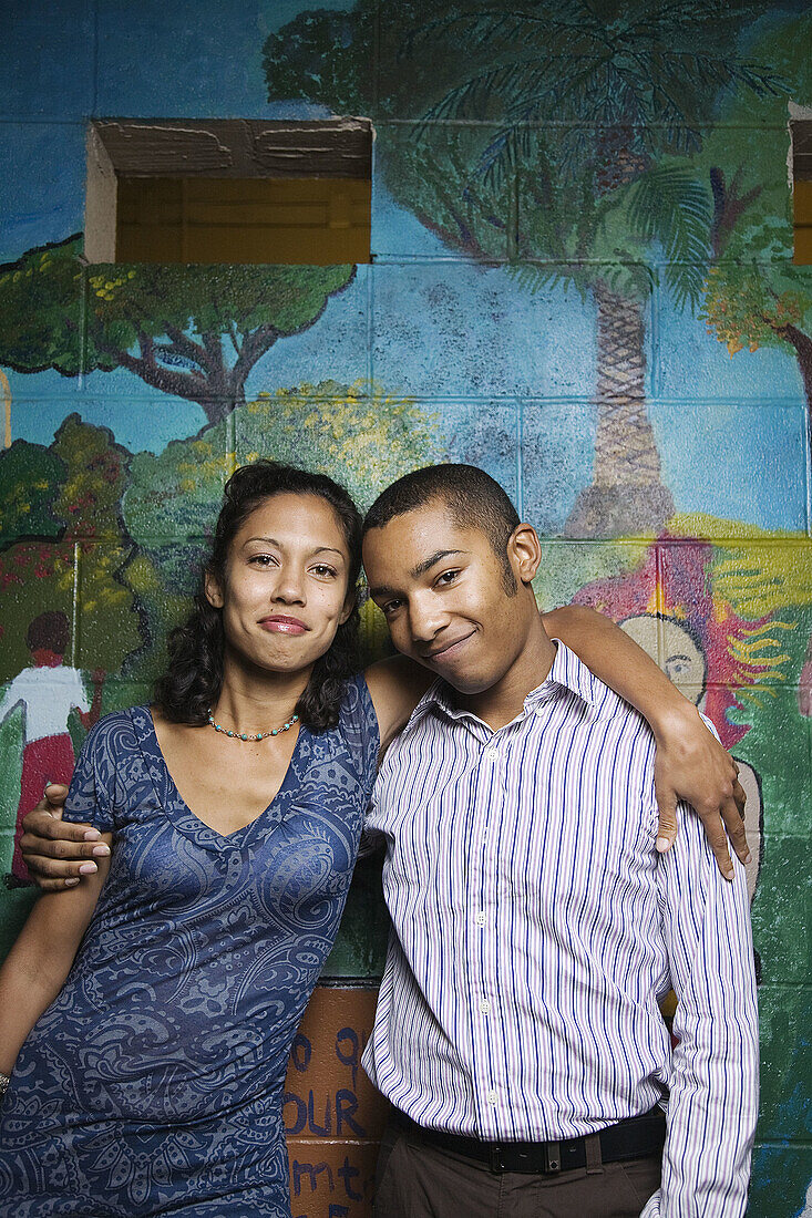 A young man and young woman in front of a wall mural, Berkeley, California, USA