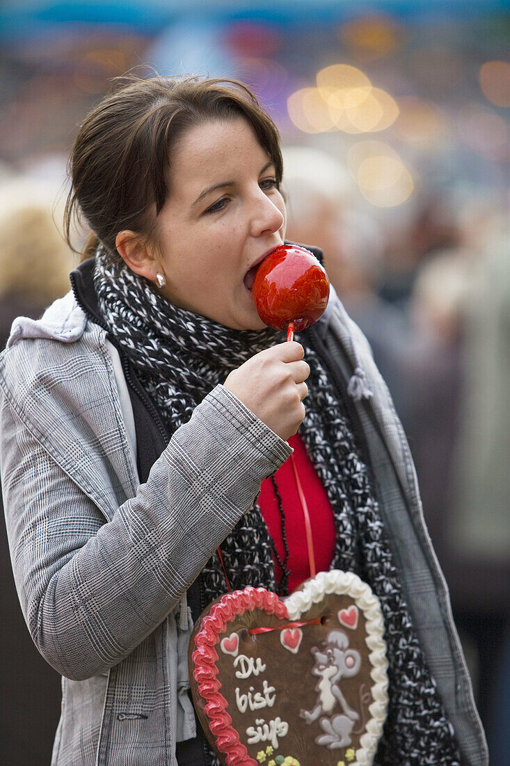A girl eating a glaced apple at the Bremen Annual Fair
