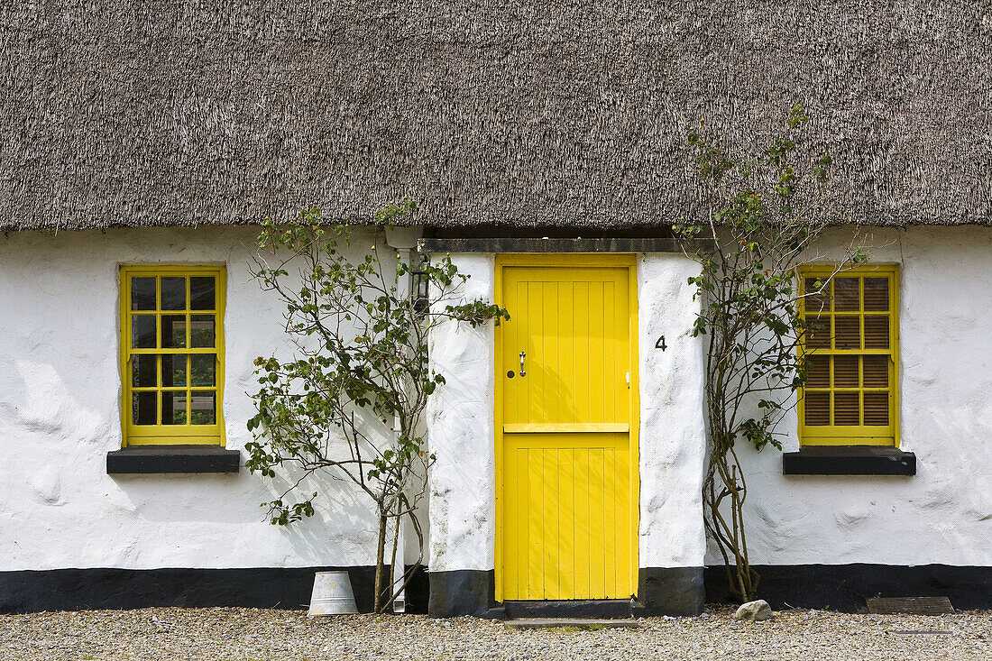 Thatched cottage with yellow door and windows in Ballyvaughan, Ireland