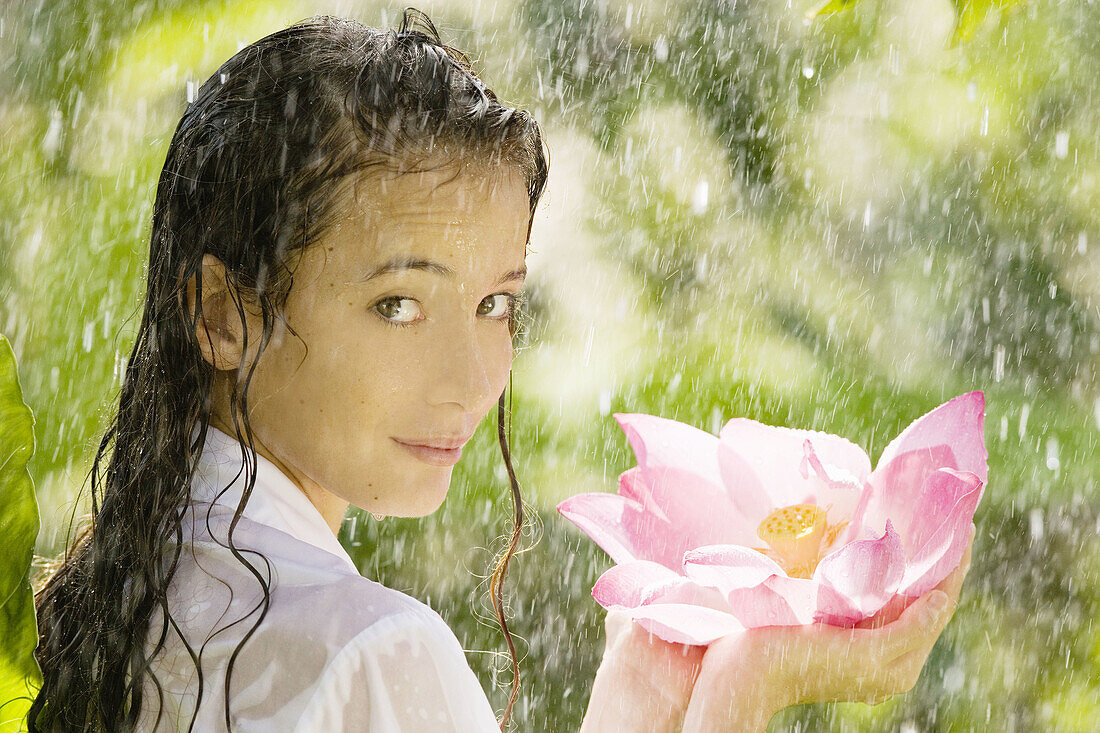 17-19, Beauty, Body care, Casual, Caucasian, Clothing, Color, Colour, Contemporary, Flower, Fragility, Freshness, Green, Head & shoulders, Head and shoulders, Health, Holding, Looking, Lotus, One person, Outdoors, Over, Pink, Portrait, Rain, Shoulder, Sho