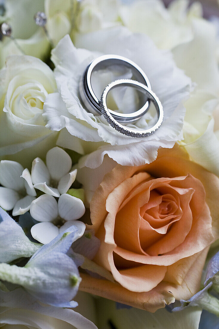 Wedding rings on top of rose flower bouquet