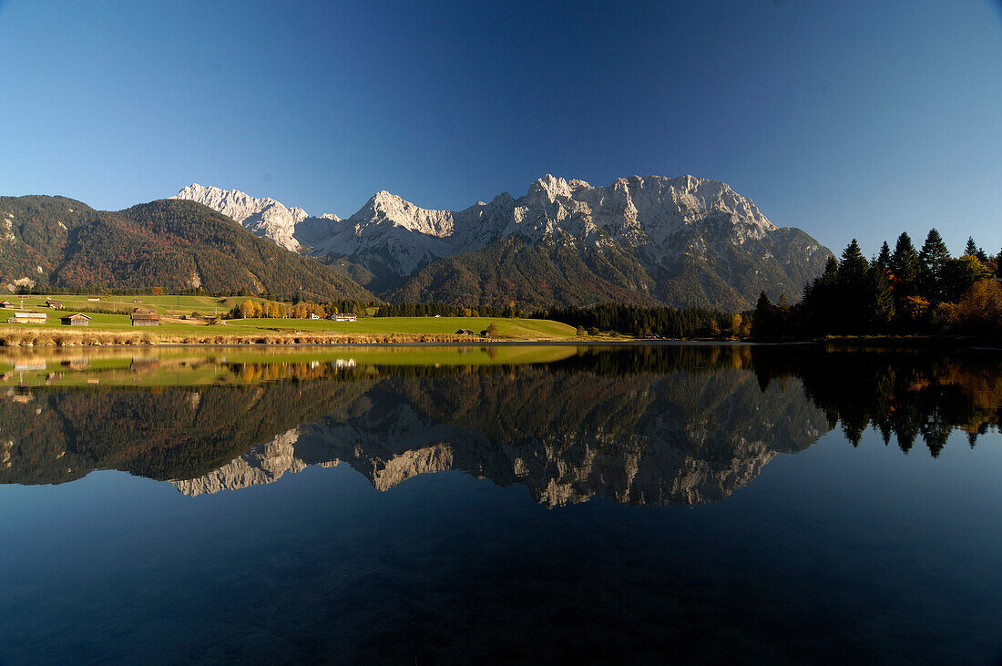 Reflection of mountains on lake Schmalensee under blue sky, Bavaria, Germany, Europe