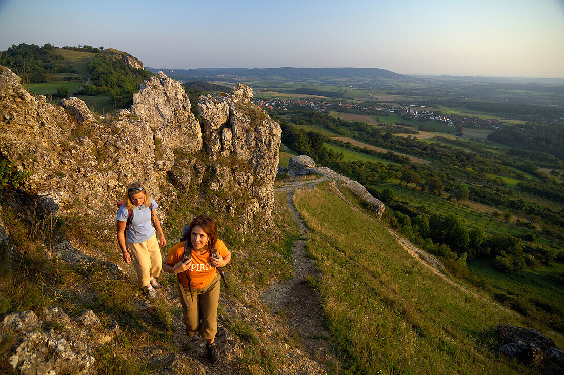 Two women hiking on a mountain in the evening sun, Walberla, Bavaria, Germany, Europe