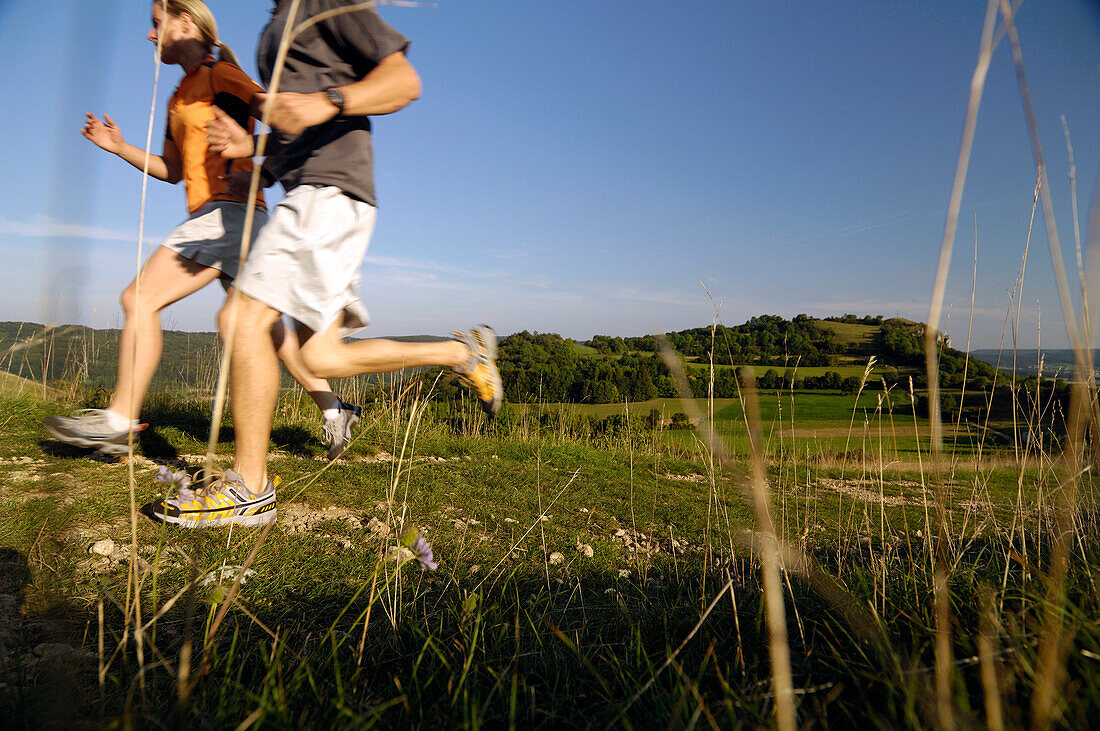 Couple jogging on a meadow, Franconian Switzerland, Bavaria, Germany, Europe