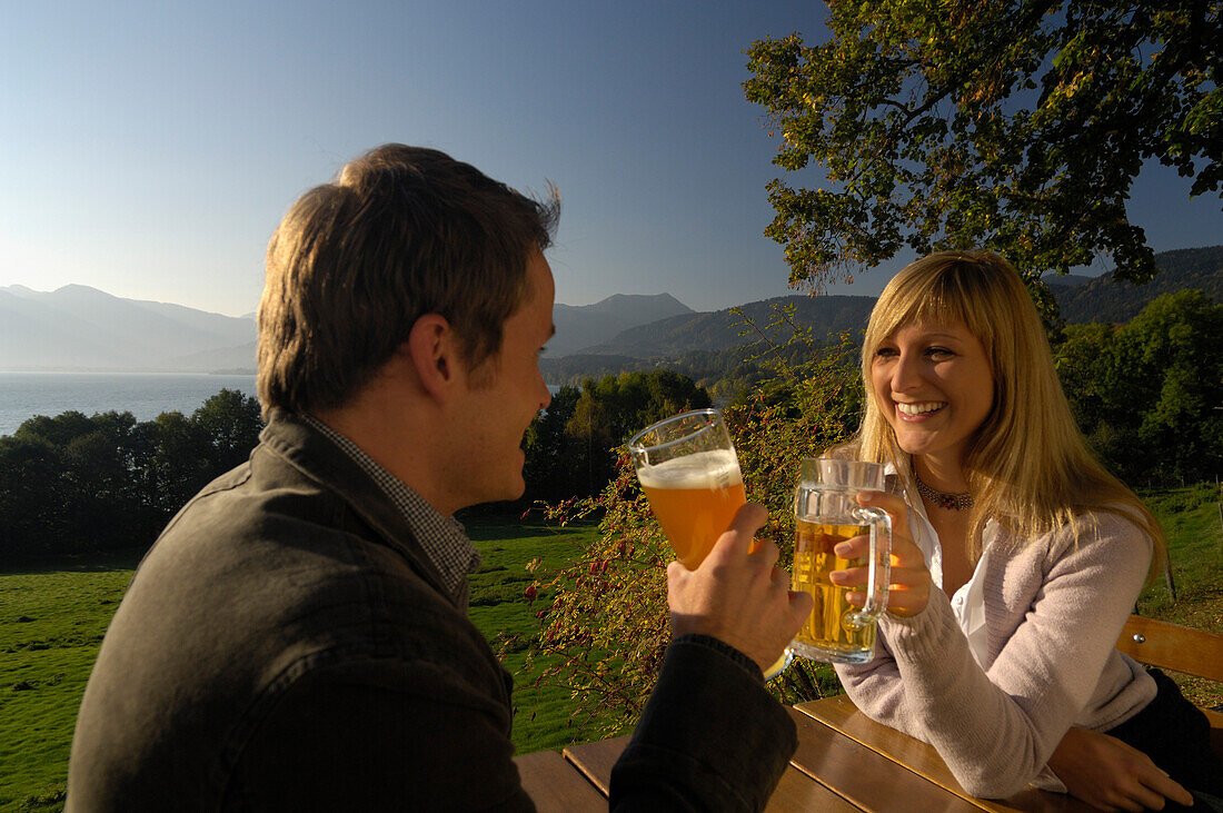 Junges Paar in einem Biergarten im Sonnenlicht, Tegernsee, Bayern, Deutschland, Europa