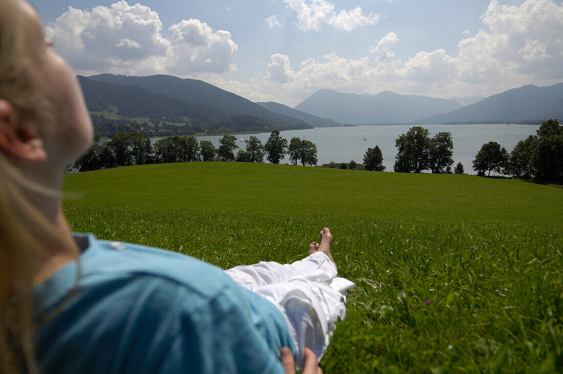 Young woman lying in the grass, near lake Tegernsee, Upper Bavaria, Bavaria, Germany