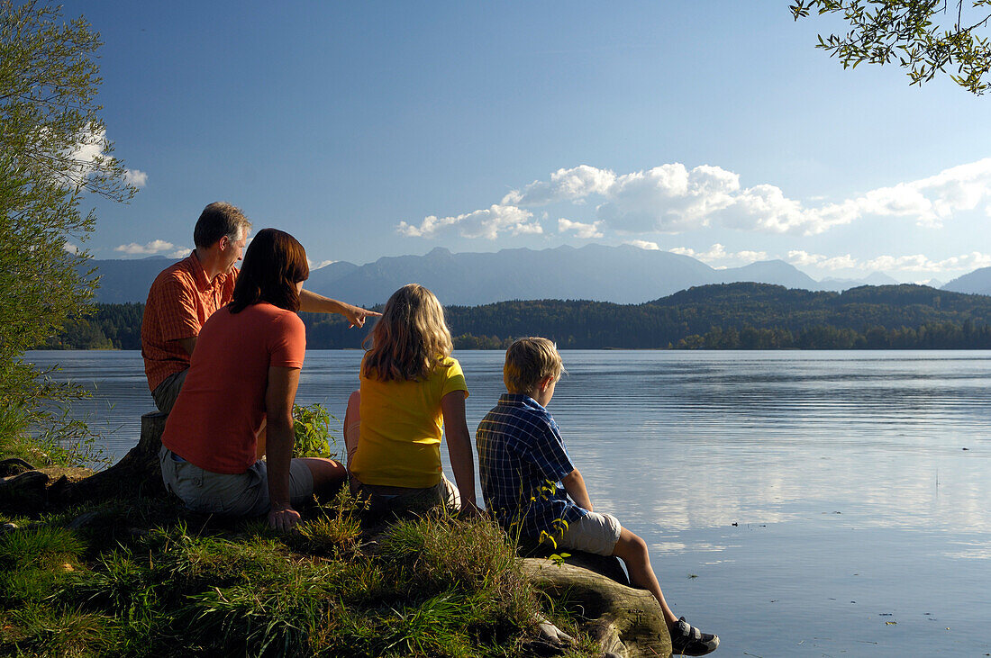 Family sitting on the shore of lake Staffelsee, near Murnau, Upper Bavaria, Bavaria, Germany
