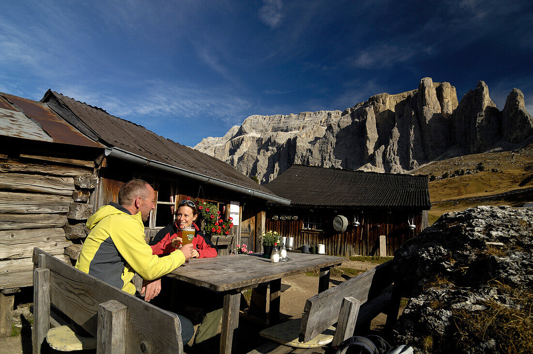 Couple having a rest at an alpine hut, near Wolkenstein, view of Sella mountains, Gardena Valley, Dolomites, South Tyrol, Italy, Europe