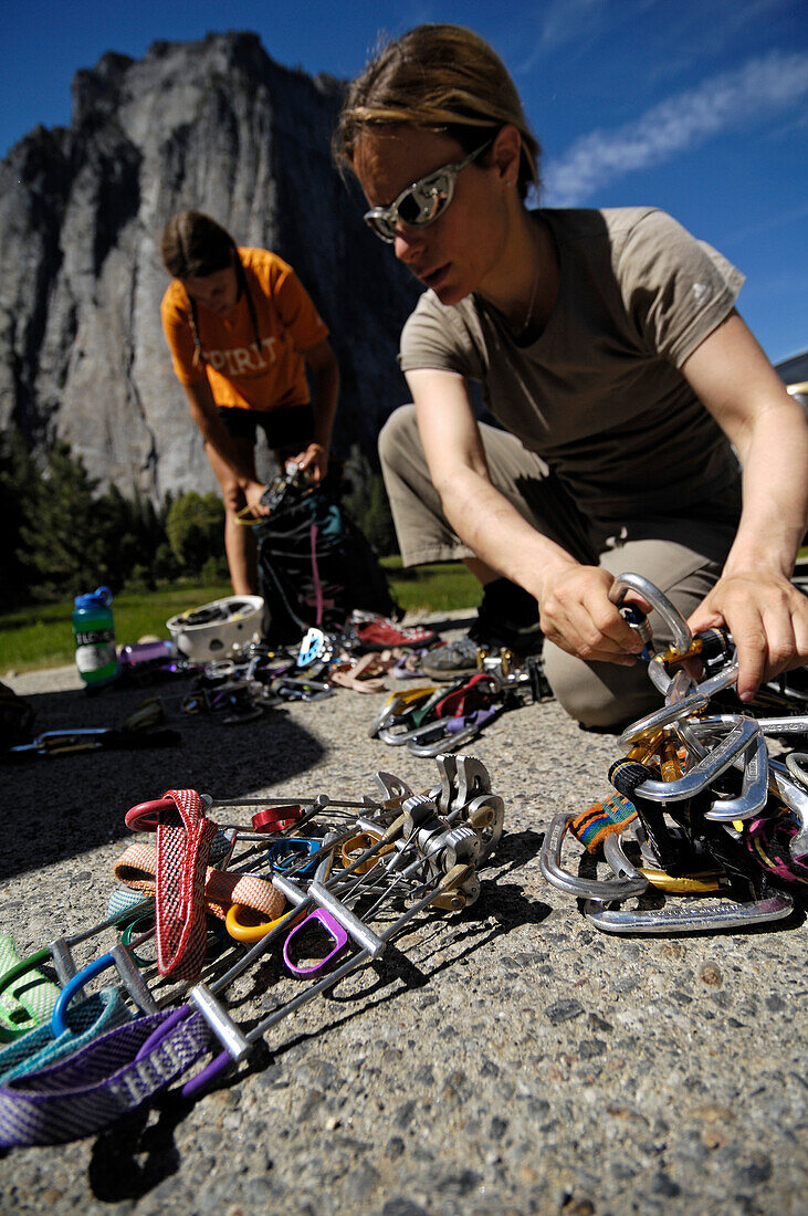 Two women sorting their climbing equipment, quickdraws, cams and friends, Yosemite National Park, California, USA