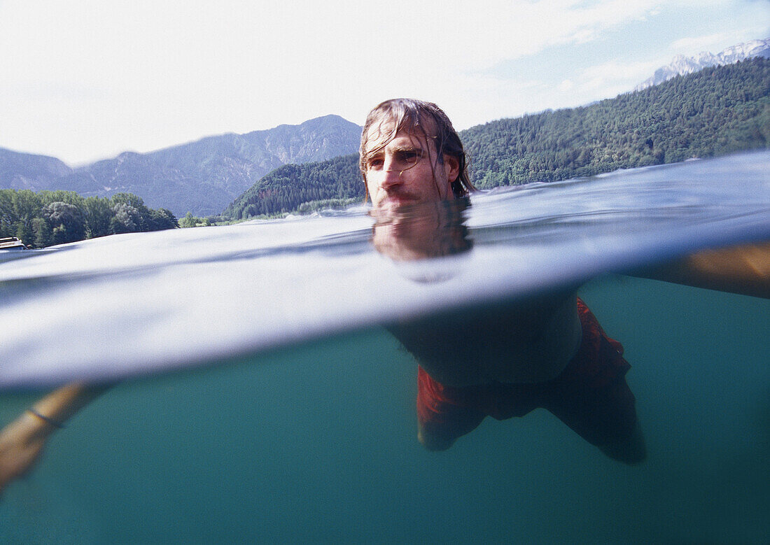 Junger Mann schwimmt im den Lago di Levico, Valsugana, Trentino-Südtirol, Italien