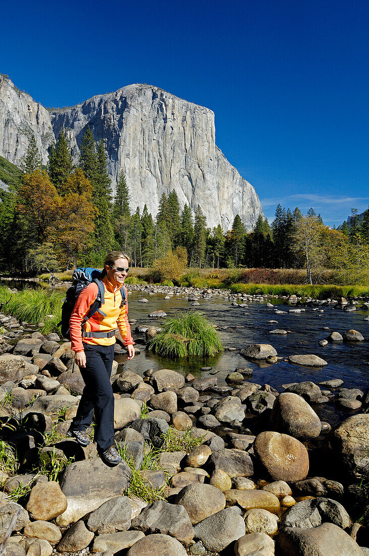 Frau mit Rucksack wandert über Steine am Bachufer, Yosemite Nationalpark, Kalifornien, Nordamerika, Amerika