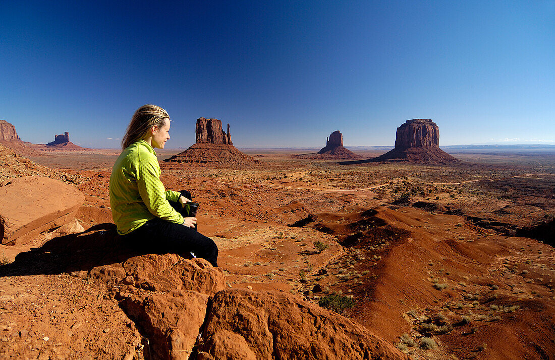 Young woman sitting on a rock looking at the view, Monument Valley, Utah, North America, America