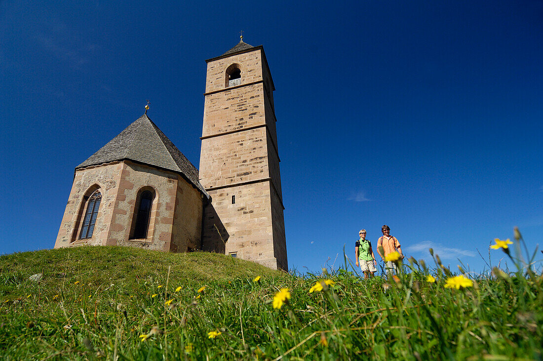 Hikers standing beside a church under blue sky, South Tyrol, Italy, Europe