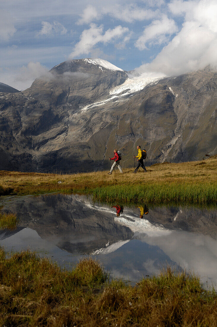 Hikers in front of a mountain lake under clouded sky, Hohe Tauern, Austria, Europe