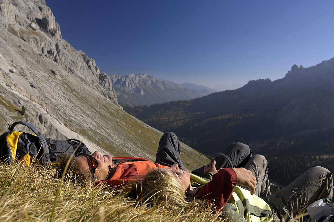 Couple resting on mountain meadow, Val di Fassa, Dolomites, Trentino-Alto Adige/Südtirol, Italy