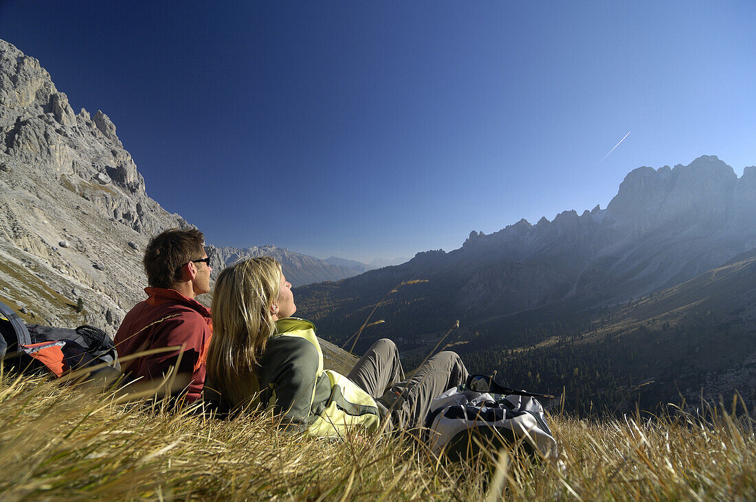 Couple resting on mountain meadow, Val di Fassa, Dolomites, Trentino-Alto Adige/Südtirol, Italy