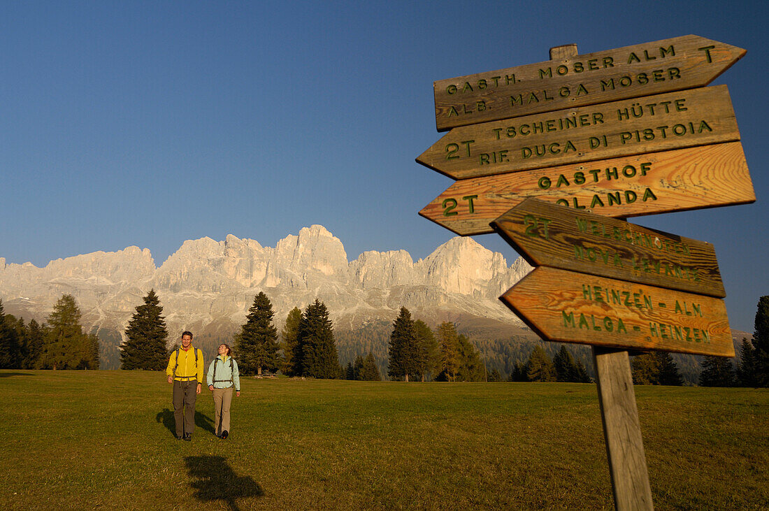 Wanderer an einem Wegweiser im Licht der Abendsonne, Rosengarten, Dolomiten, Südtirol, Italien, Europa