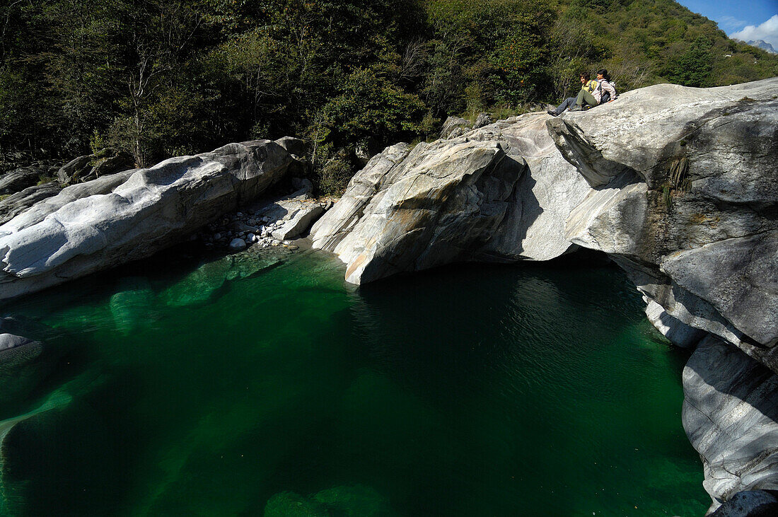 Paar sitzt auf Felsen an einem Fluss im Sonnenlicht, Verzasca Tal, Tessin, Schweiz, Europa