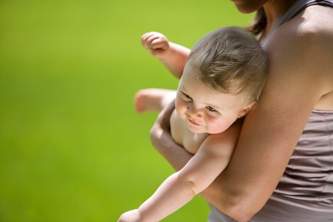 Mother holding baby on meadow, 9 months