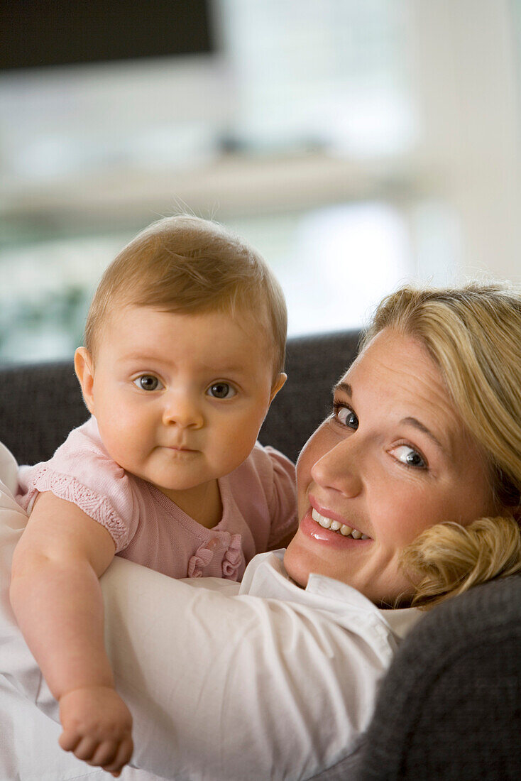 Frau mit Baby lächelt in Kamera, 8 Monate