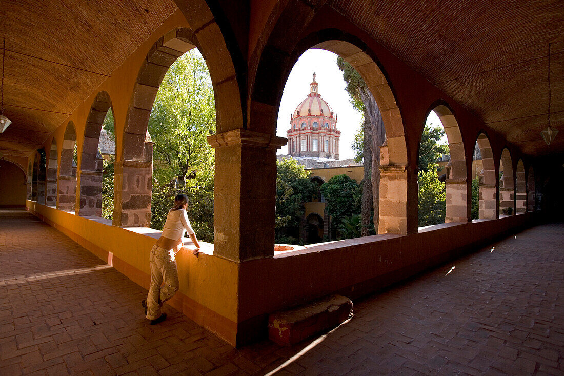 Schwangere Frau schaut in den Innenhof eines alten mexikanischen Gebäudes, Bellas Artes, San Miguel de Allende, Guanajuato, Mexiko