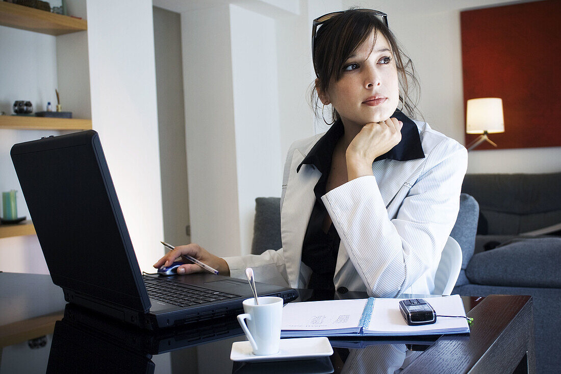 Young executive meditating while working on her laptop