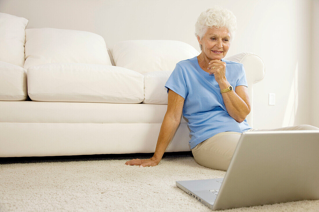 Adult, Adults, At home, Calm, Calmness, Caucasian, Caucasians, Color, Colour, Computer, Computers, Contemporary, Couch, Couches, Female, Gray-haired, Grey hair, Grey haired, Grey hairs, Grey-haired, Home, human, indoor, indoors, interior, Laptop, Laptop c