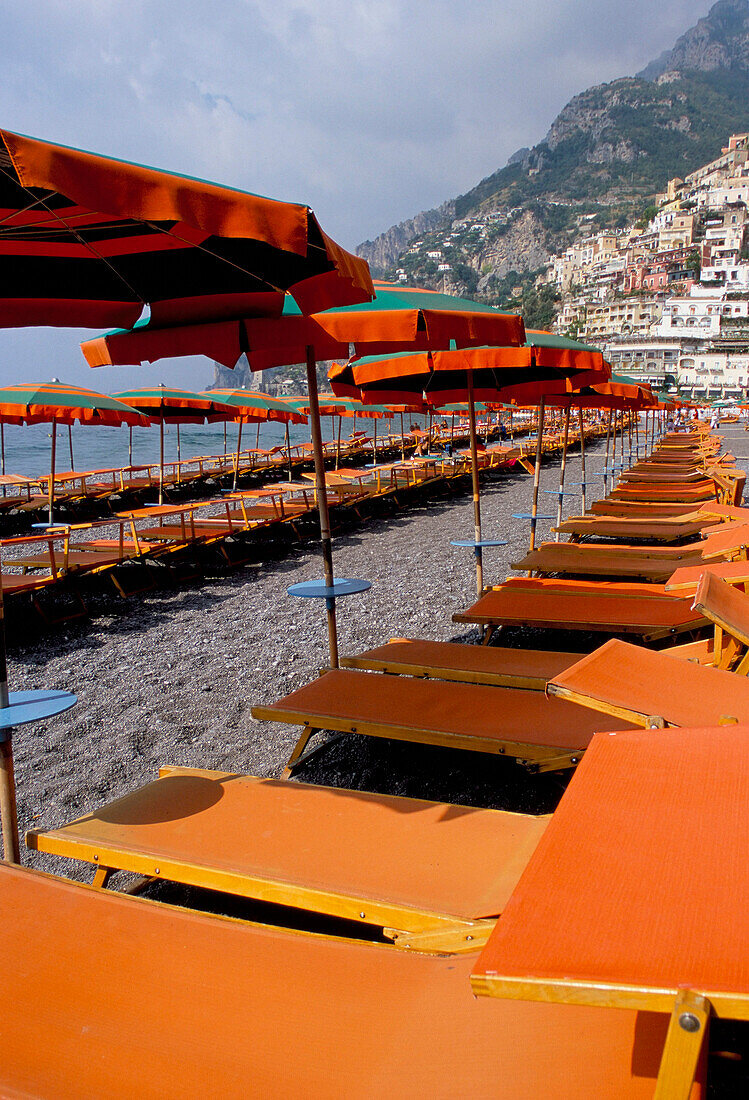 Beach with colourful orange sun loungers and umbrellas, Positano, Campania, Italy