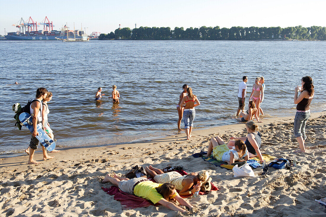 Young people at sandy beach of river Elbe, Oevelgoenne, Hamburg, Germany