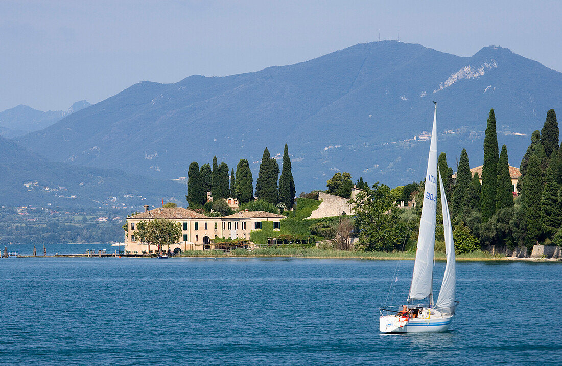 Segelboot steuert Punta San Vigilio bei Garda an. Das Haus an der Lanspitze ist das älteste Hotel am Gardasee, Provinz Verona, Veneto, Italien