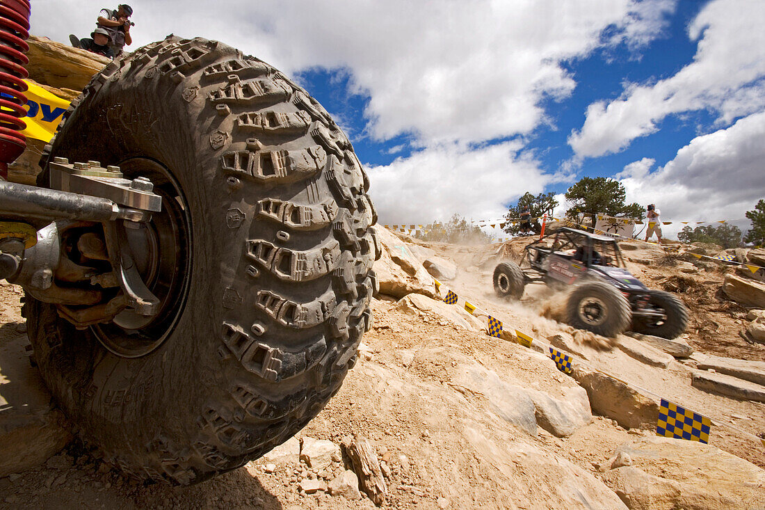 Blick auf einen Rennwagenreifen bei einem Rock Crawling Rennen wo im Hintergrund ein Rennwagen vorbei fährt, Rock Crawling, Moab, Utah, USA