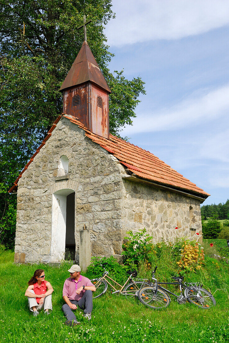 Cyclists resting near a chapel, Bad Koetzting, Bavarian Forest, Upper Palatinate, Bavaria, Germany