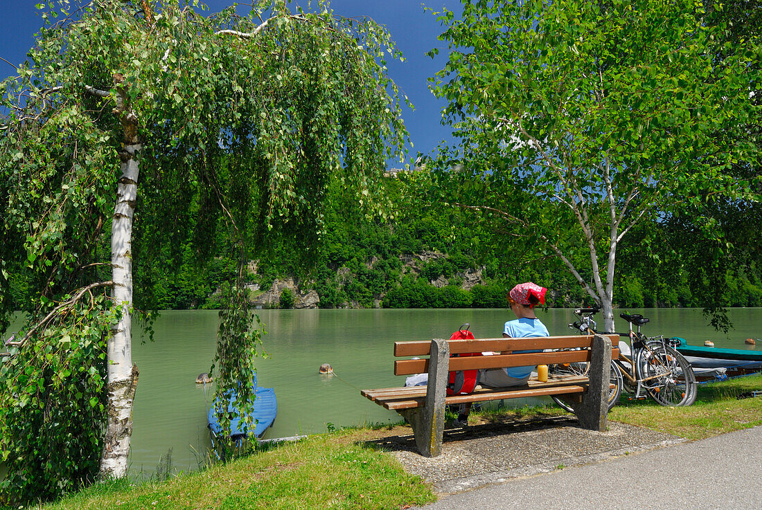 Frau sitzt auf Bank am Ufer der Donau, Donauradweg Passau Wien, Oberösterreich, Österreich