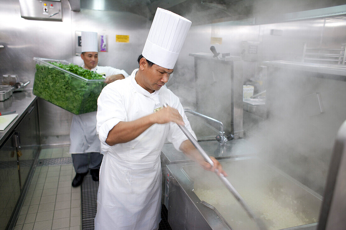 Galley on board a cruise ship, Cooks in the kitching preparing vegetables, Cruise liner Queen Mary 2