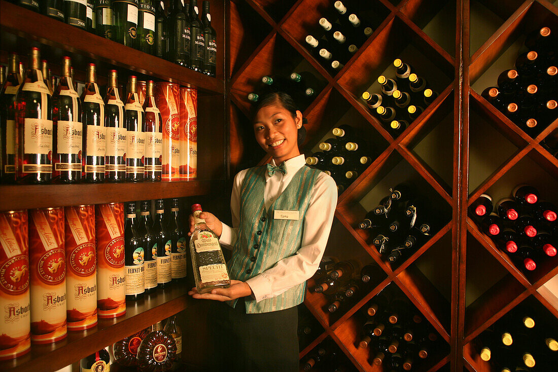 Junge Angestellte vor einem Weinregal im Peacock Garden Resort, Baclayon, Bohol, Philippinen, Asien