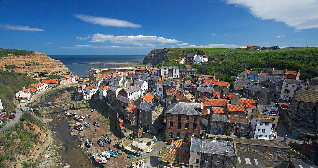 View over fishing village and harbour at low tide, Staithes, Yorkshire, UK, England