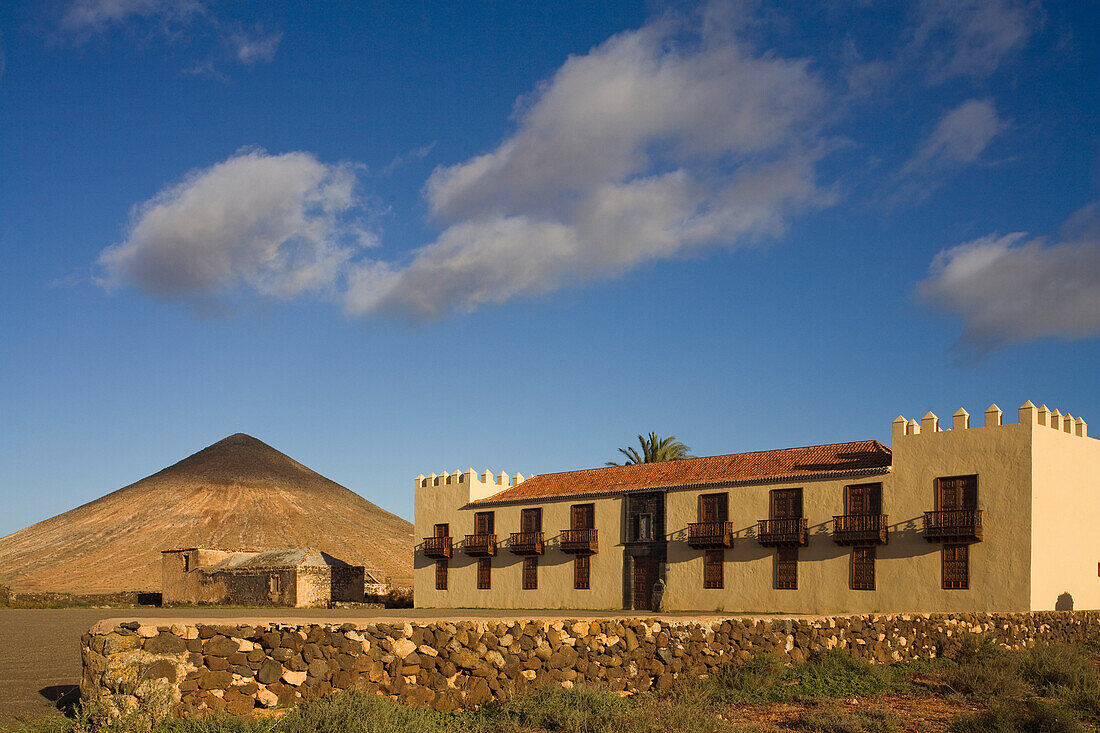 The extinct volcano Montana Oliva behind the historical building Casa de Los Coroneles, La Oliva, Fuerteventura, Canary Islands, Spain, Europe