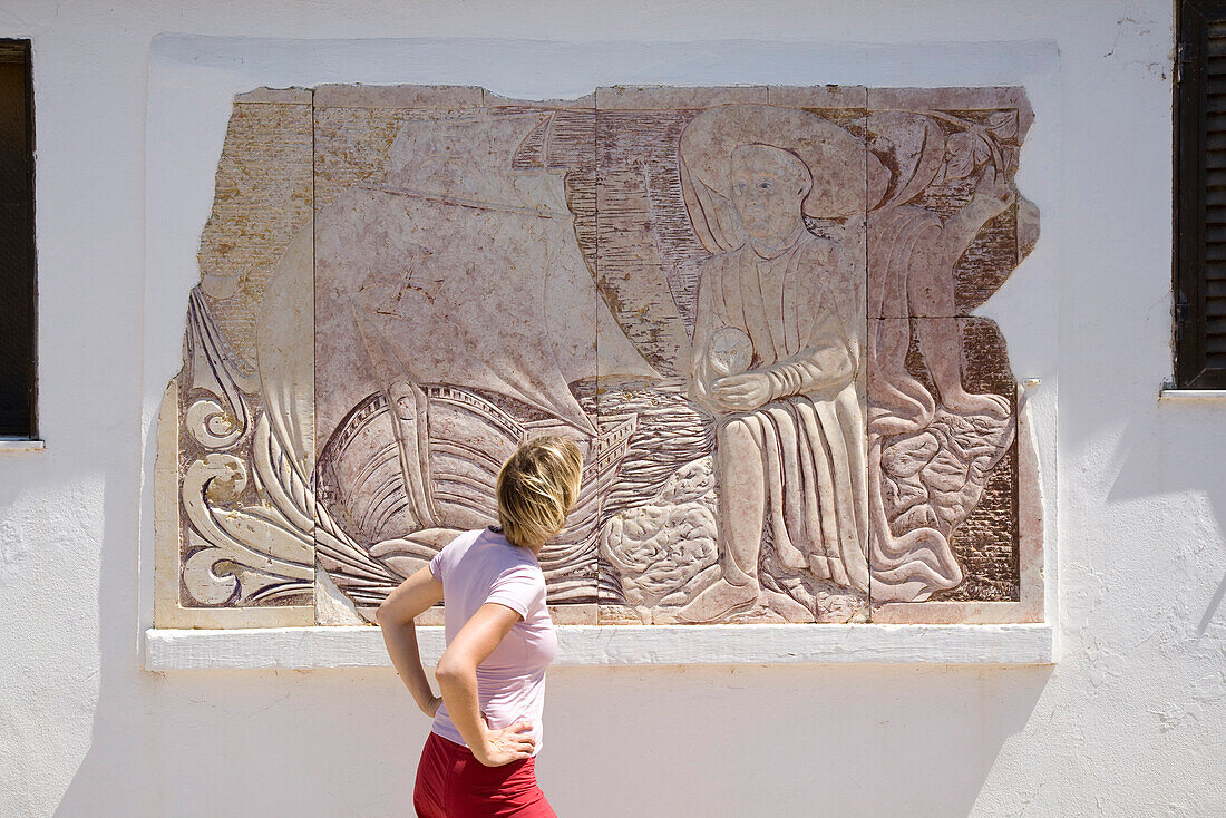 Young women looking at the stone mural of Henry the Navigator (15th century), MR, West coast of Algarve, Sagres, Algarve, Portugal