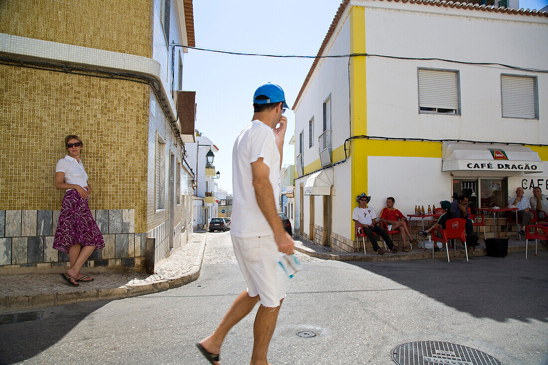 Strassenszene, junge Frau, Passant und Männer in einem Strassencafe, Siesta, Alvor, Algarve, Portugal