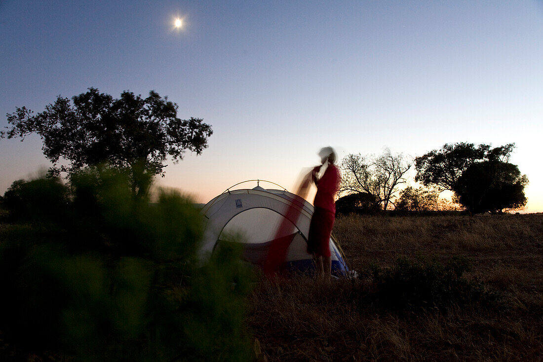 Zelten im Hinterland von Alcoutim, junge Frau blaest Matratze auf, in Portugal ist freies zelten erlaubt, Alcoutim,  Algarve, Portugal