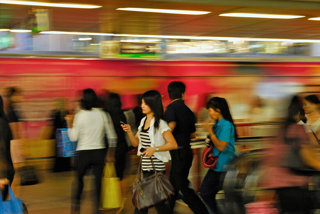 Frauen mit Handy in Bewegungsunschärfe am Bahnhof des Skytrain am Siam Square, Downtown Bangkok, Thailand, Asien