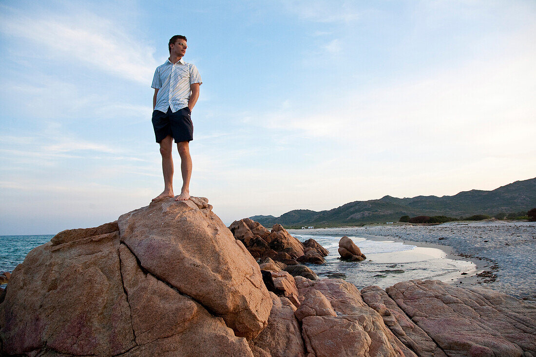 Young men on a rock at the beach of Berchidda in the evening light, Berchidda, Siniscola, Sardinia, Italy, Europe