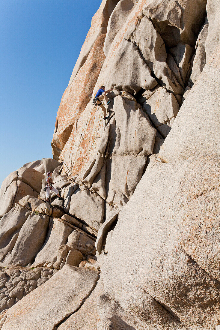 Kletterer an Granitfelsen unter blauem Himmel, Capo Testa, Sardinien, Italien, Europa