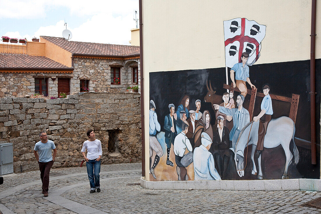Tourists looking at mural painting at a house, Orgosolo, Sardinia, Italy, Europe