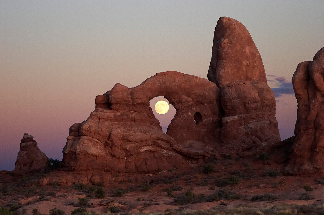 Moon framed by Turret Arch red rock formation, Arches National Park, Utah, USA